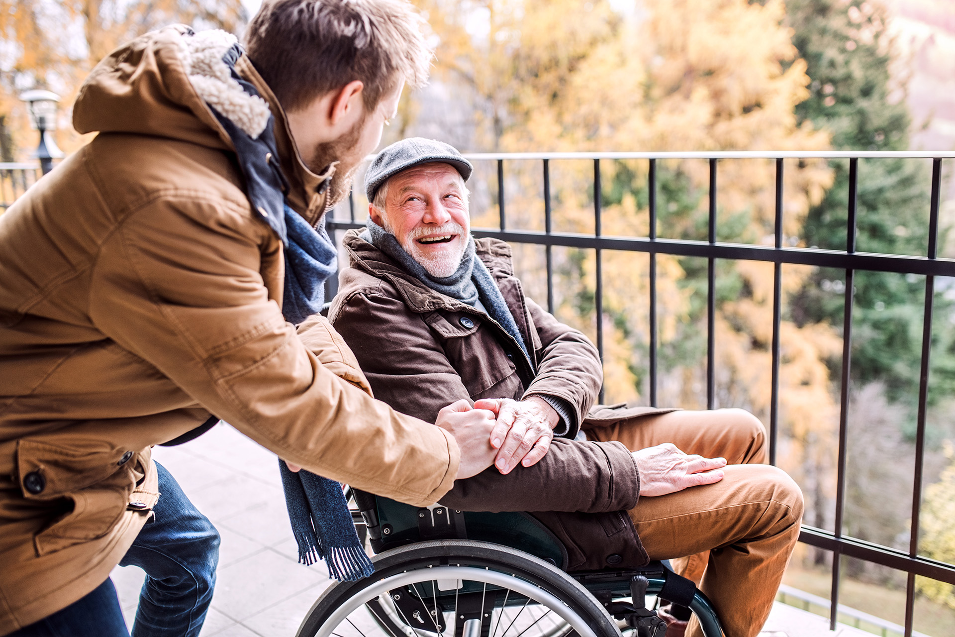 Junger Mann pflegt seinen Großvater im Rollstuhl